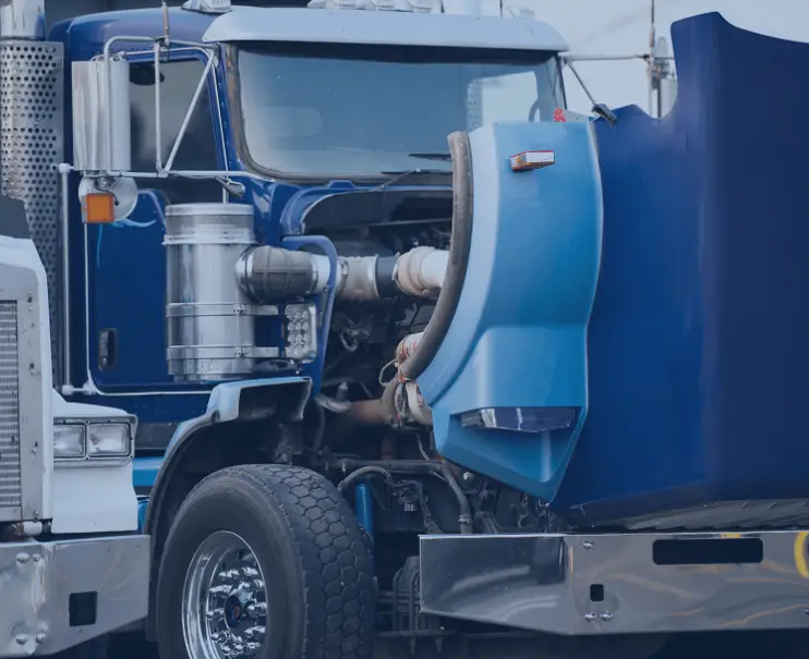 A close-up of a blue semi-truck with its hood open showing the engine.