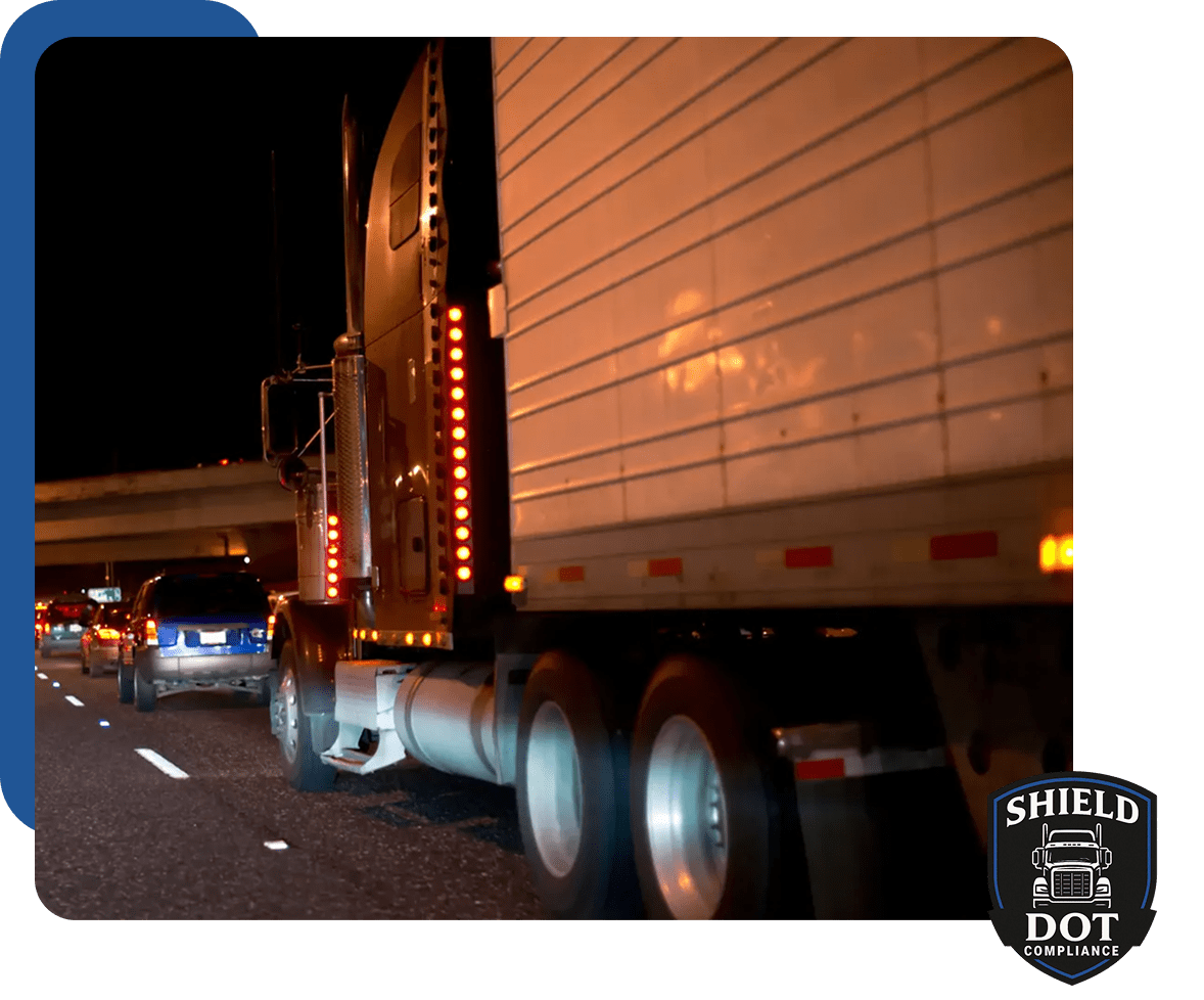 A large truck driving at night with several cars behind it.